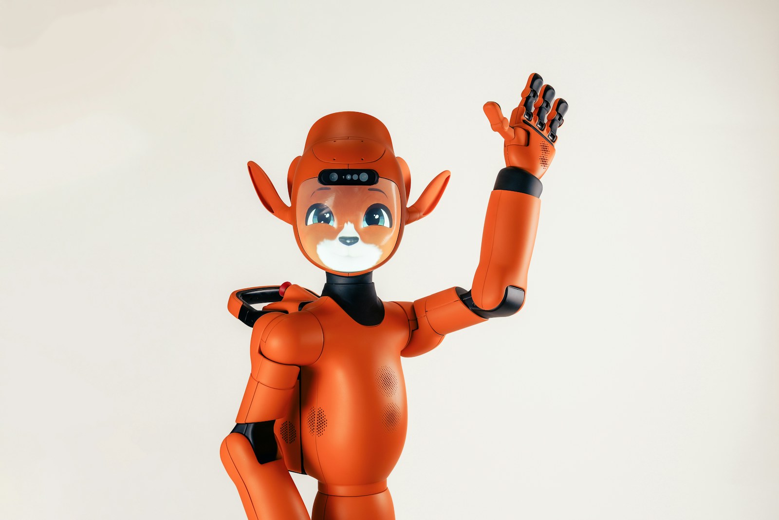An orange humanoid robot with animal-like ears waving its hand against a white background