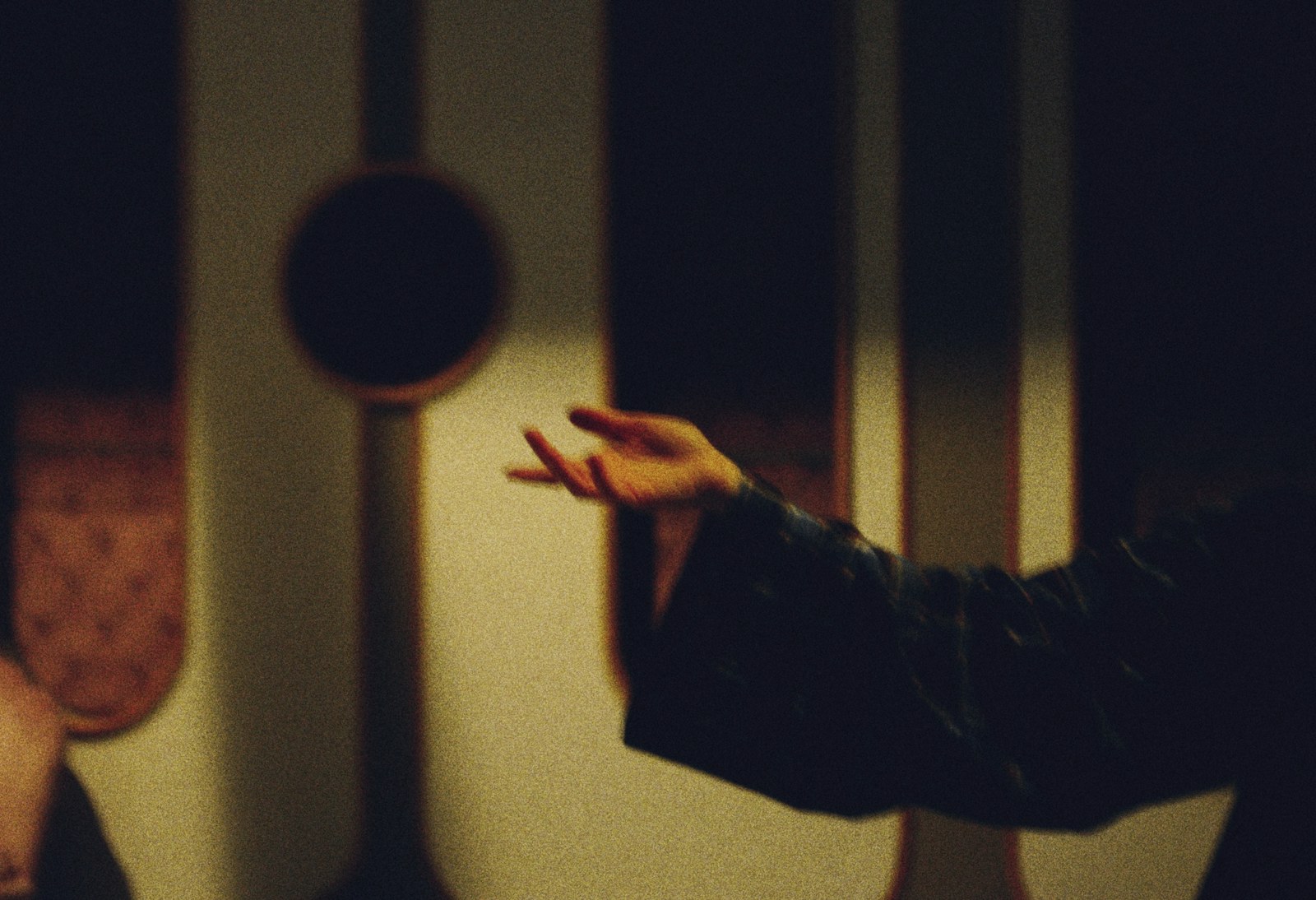 A person's hand reaching out in a dimly lit room