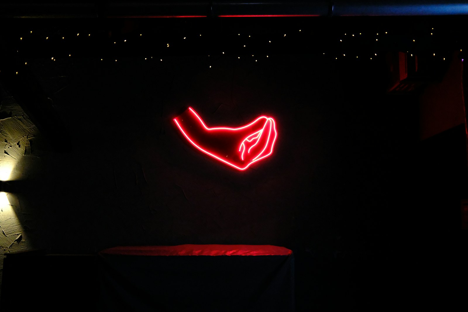 Red neon hand sign glows in dark room
