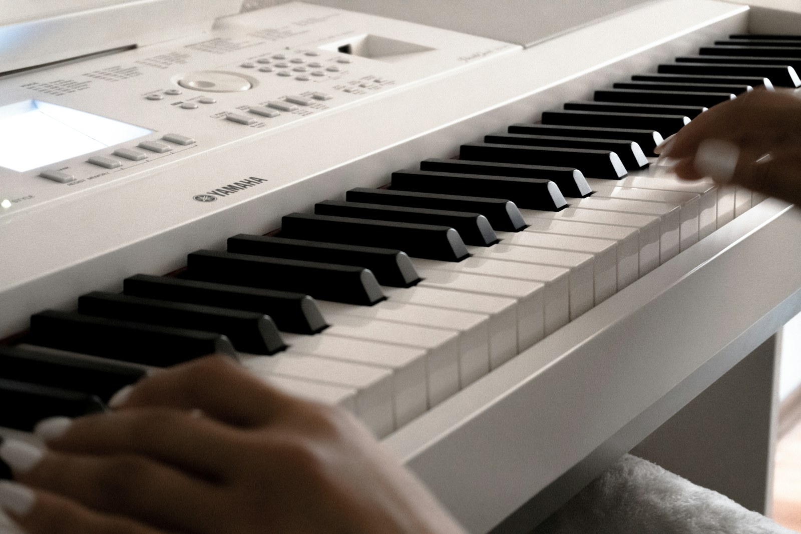 Hands playing a white digital piano keyboard