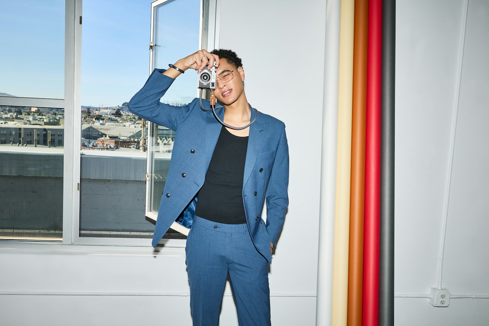 A stylish man in a blue suit holds a camera