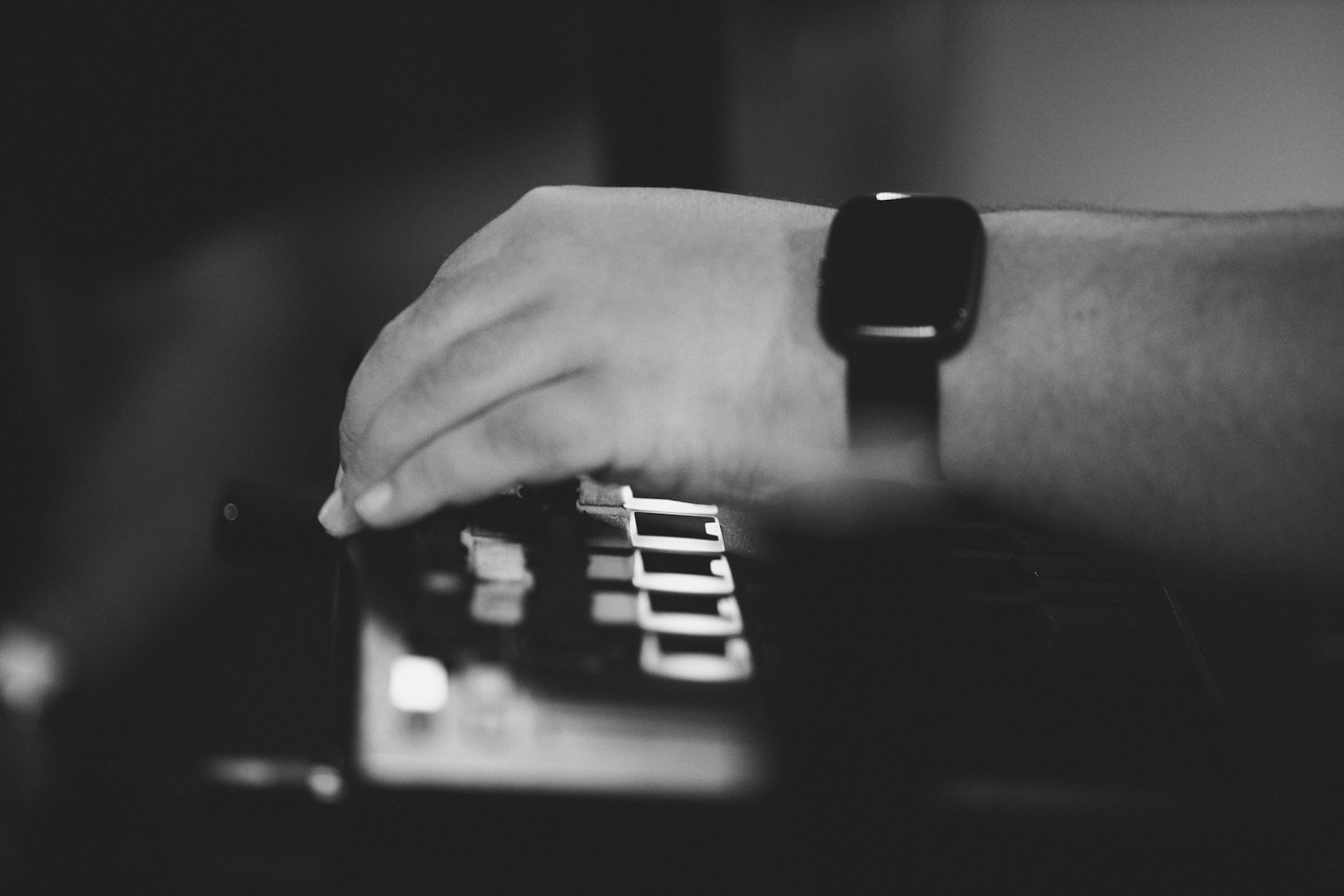 A hand wearing a smartwatch playing piano keys